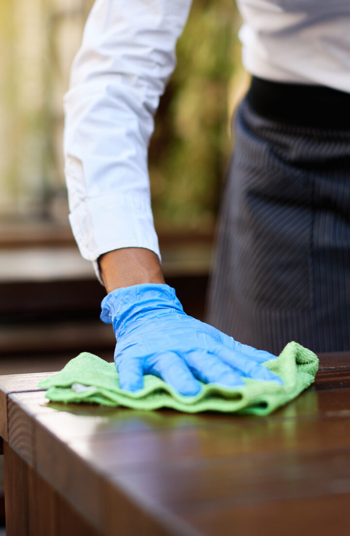 Close-up of waitress disinfecting tables at outdoor cafe during coronavirus epidemic.