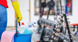 Gym cleaning concept. Cleaning lady stands with a bucket and cleaning products on the background of the gym.