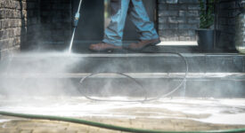 Pressure Washer Cleaning Time. Men Cleaning Outside House Stairs with Power High Pressured Cleaner. Ceramic Stairs and Home Entrance. Closeup Photo.