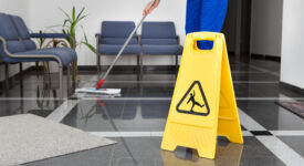 Close-up Of Man Cleaning The Floor With Yellow Wet Floor Sign
