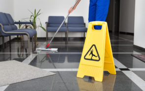 Close-up Of Man Cleaning The Floor With Yellow Wet Floor Sign