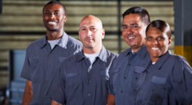 Team of multi-ethnic auto mechanics.  Focus on Caucasian man (30s).